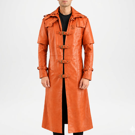A man wearing a long, bright orange leather trench coat with toggle closures and a high collar, photographed against a plain light gray studio background.