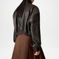 Person wearing a dark brown leather jacket and brown skirt