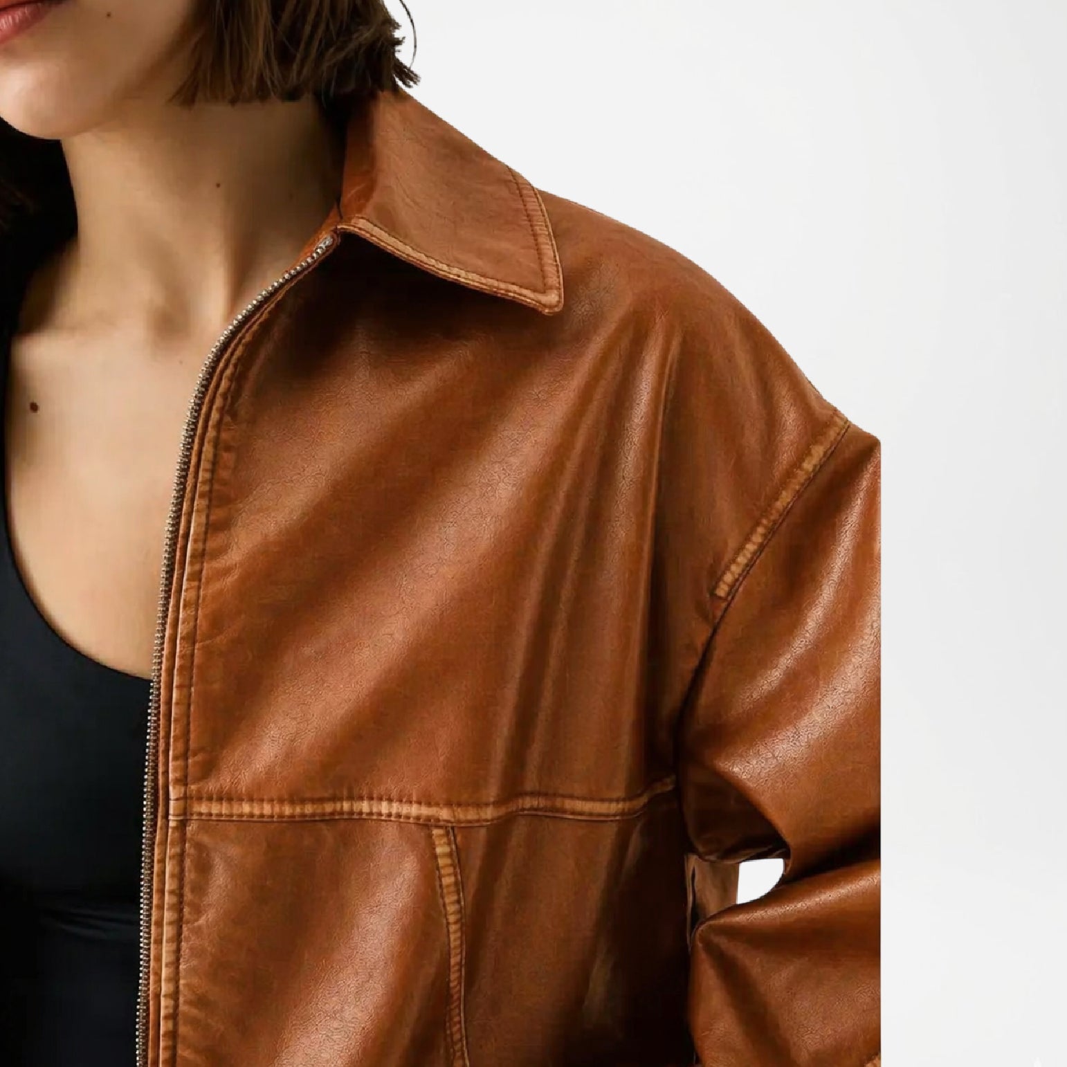 Brown leather jacket worn by a person on a white background