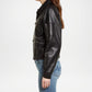 Person wearing a black leather jacket and blue jeans on a white background