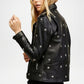 Black leather jacket with star patterns on a plain background