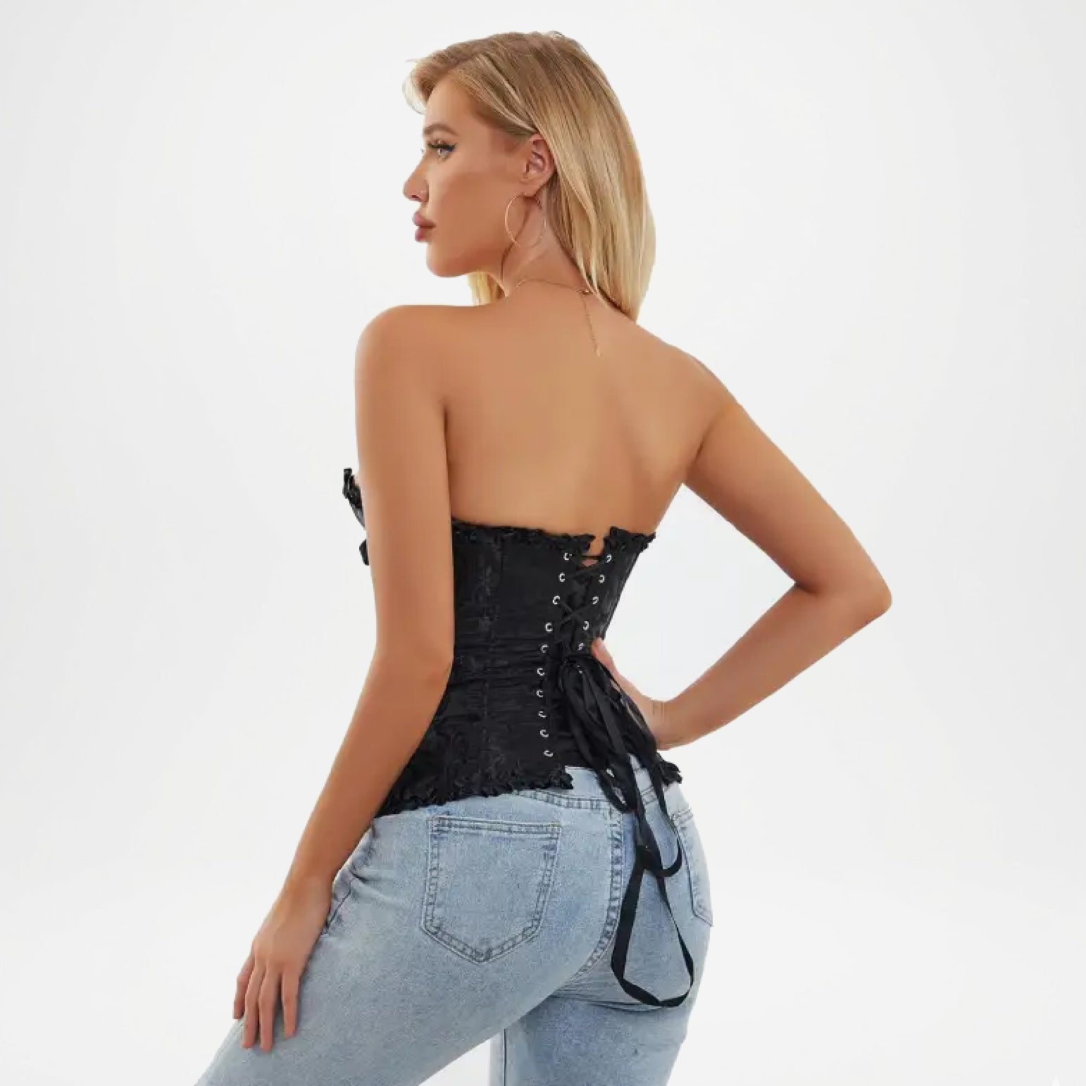 Woman wearing a black corset top and light blue jeans