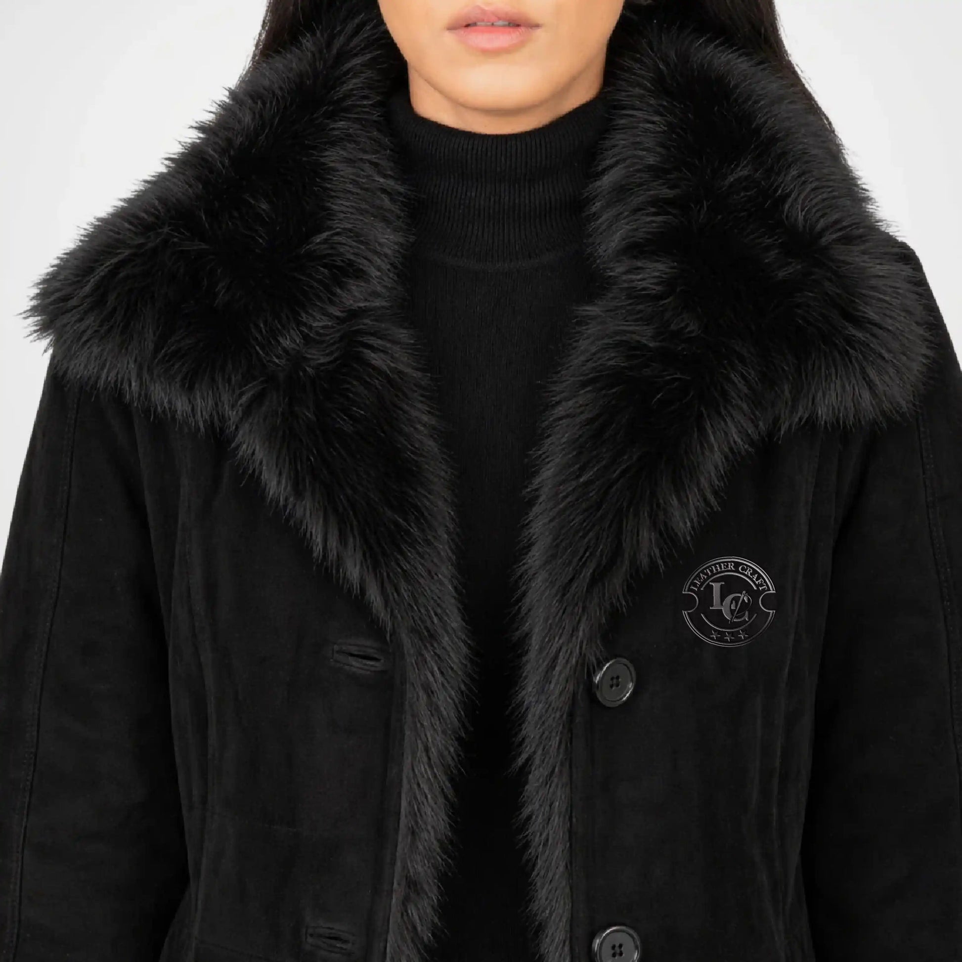 Black coat with fur collar worn by a person on a light gray background