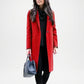 Woman wearing a red coat holding a gray handbag