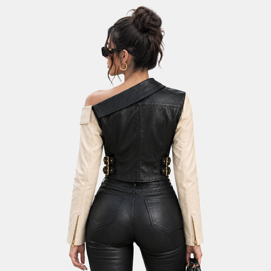 A woman shown from the back wearing a one-shoulder faux leather jacket with a black yoke and cream sleeves, paired with black leather pants, against a light gray studio background.