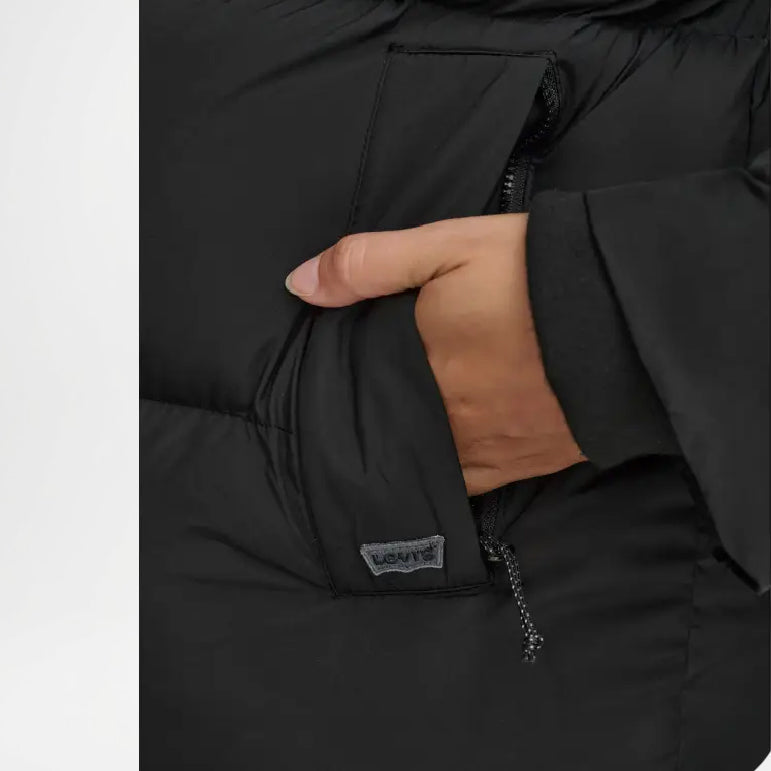 Close-up of a hand adjusting the hood of a black puffer jacket