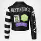 Black faux leather Beetlejuice jacket shown from the back, featuring white text, black and white stripes on one sleeve, and several colorful graphic patches including 'Say It Times', 'Strange and Unusual', and 'Never Trust the Living'.