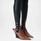 Brown pointed-toe shoes with black wedge soles worn with black leggings on a light gray background