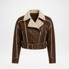 A brown faux-leather aviator-style jacket with a beige sherpa lining, featuring a belted waist, zippered front, and silver-tone hardware on a light gray background.