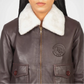 Brown leather jacket with white fur collar and brand logo