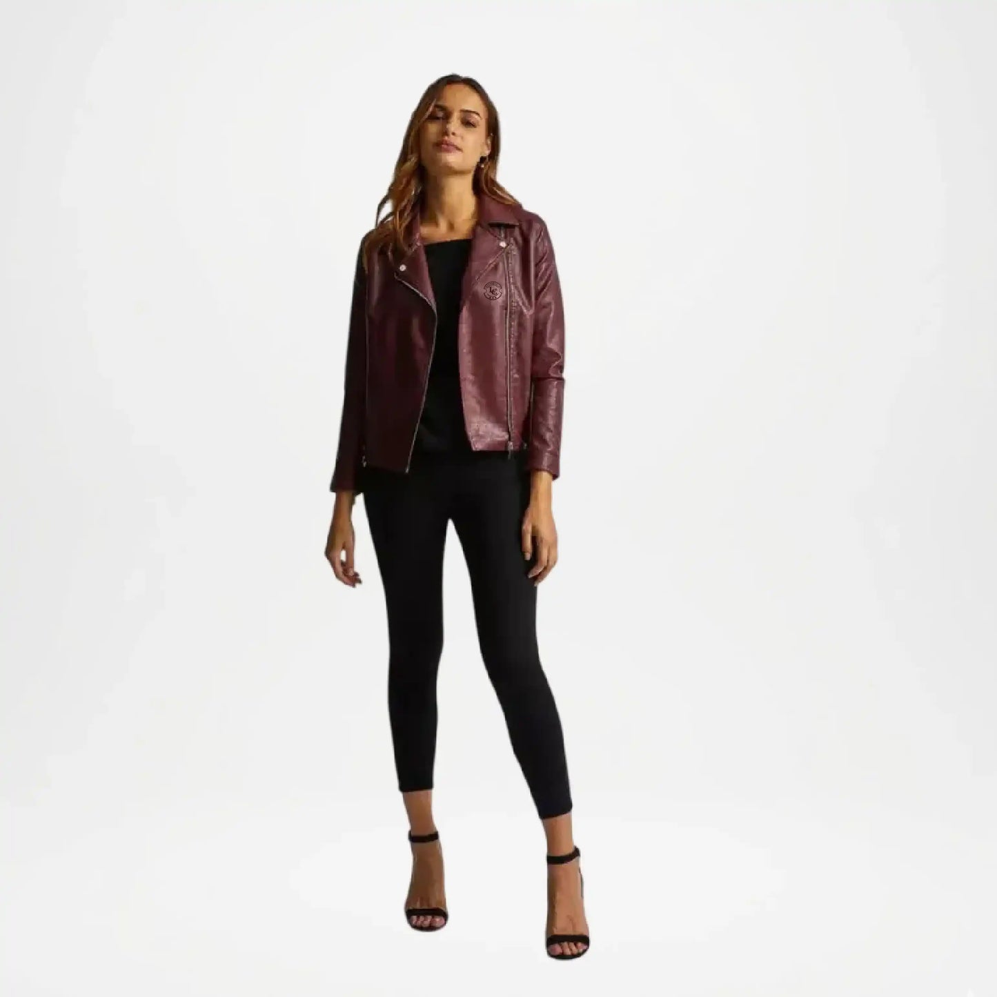 Woman wearing a burgundy leather jacket and black pants on a white background