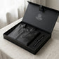 Black leather jacket and pen set in a branded box on a light surface.