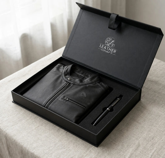 Black leather jacket and pen set in a branded box on a light surface.