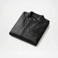Folded black leather jacket on a light gray background