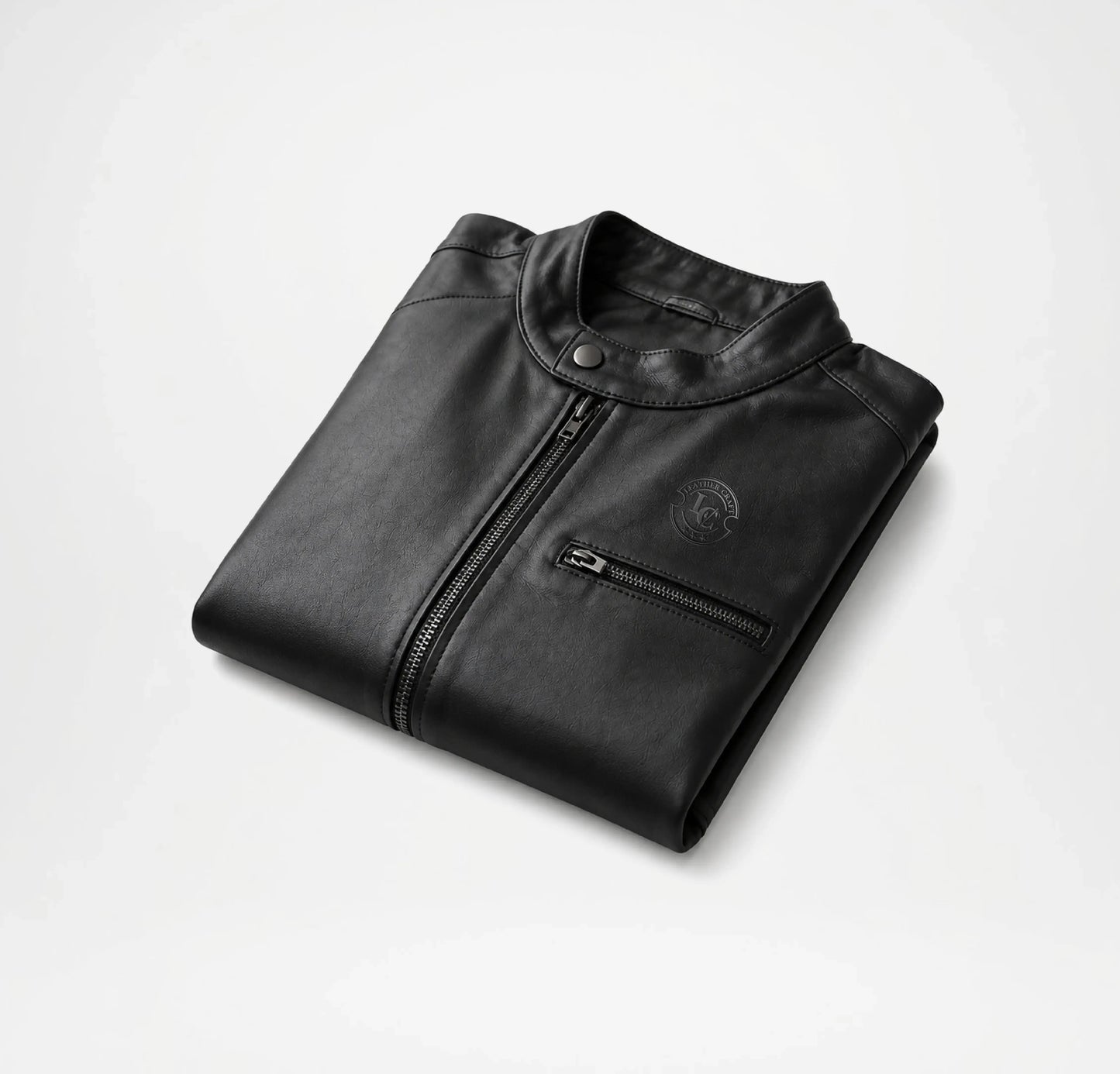 Folded black leather jacket on a light gray background