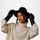 Woman wearing a black hat, beige sweater, and black gloves