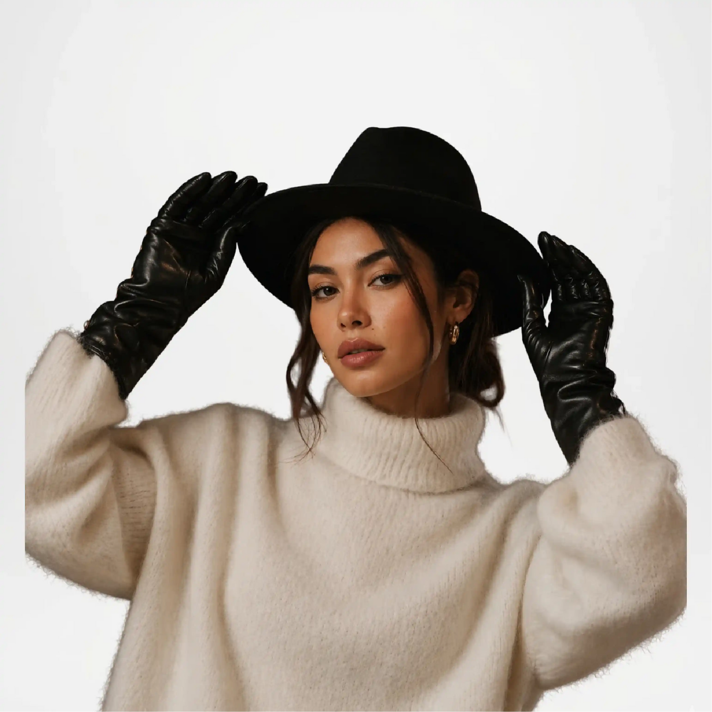 Woman wearing a black hat, beige sweater, and black gloves
