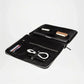 Black leather pouch with compartments holding electronic devices on a white background