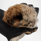Close-up of a black glove with brown fur cuff on a white background