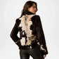 Woman wearing a brown and white cowhide jacket on a plain background