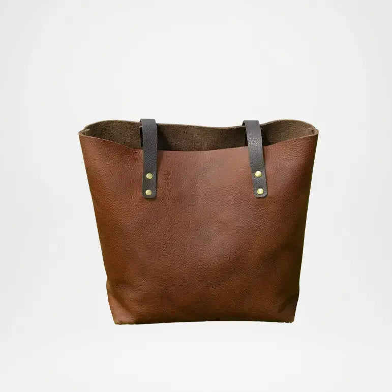 Brown leather tote bag with black straps on a light gray background