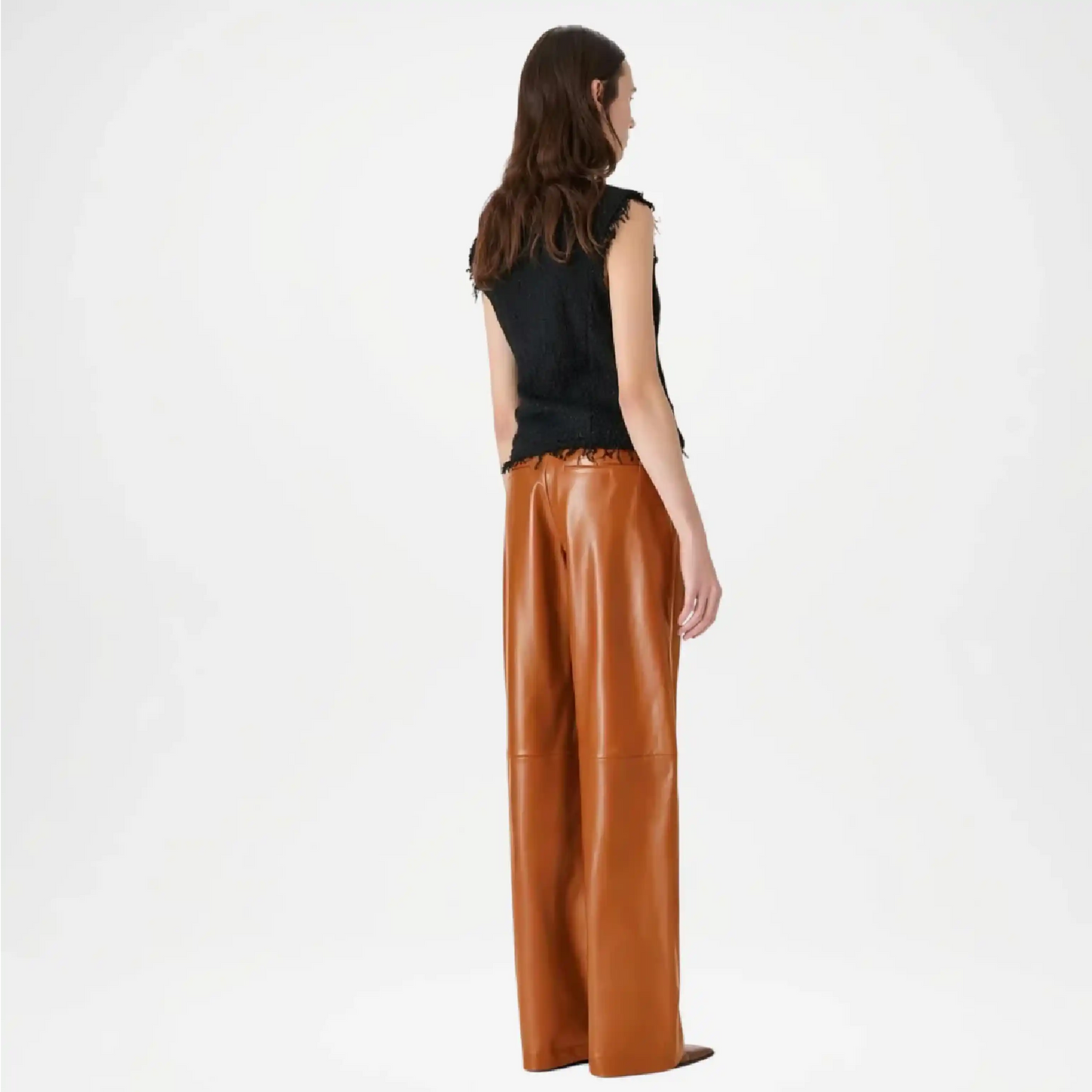 Woman wearing brown leather pants and a black top on a white background