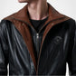 Black leather jacket with brown collar and zipper, featuring a logo on the chest.