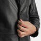 Close-up of a person wearing a black leather coat with a hand adjusting the collar.