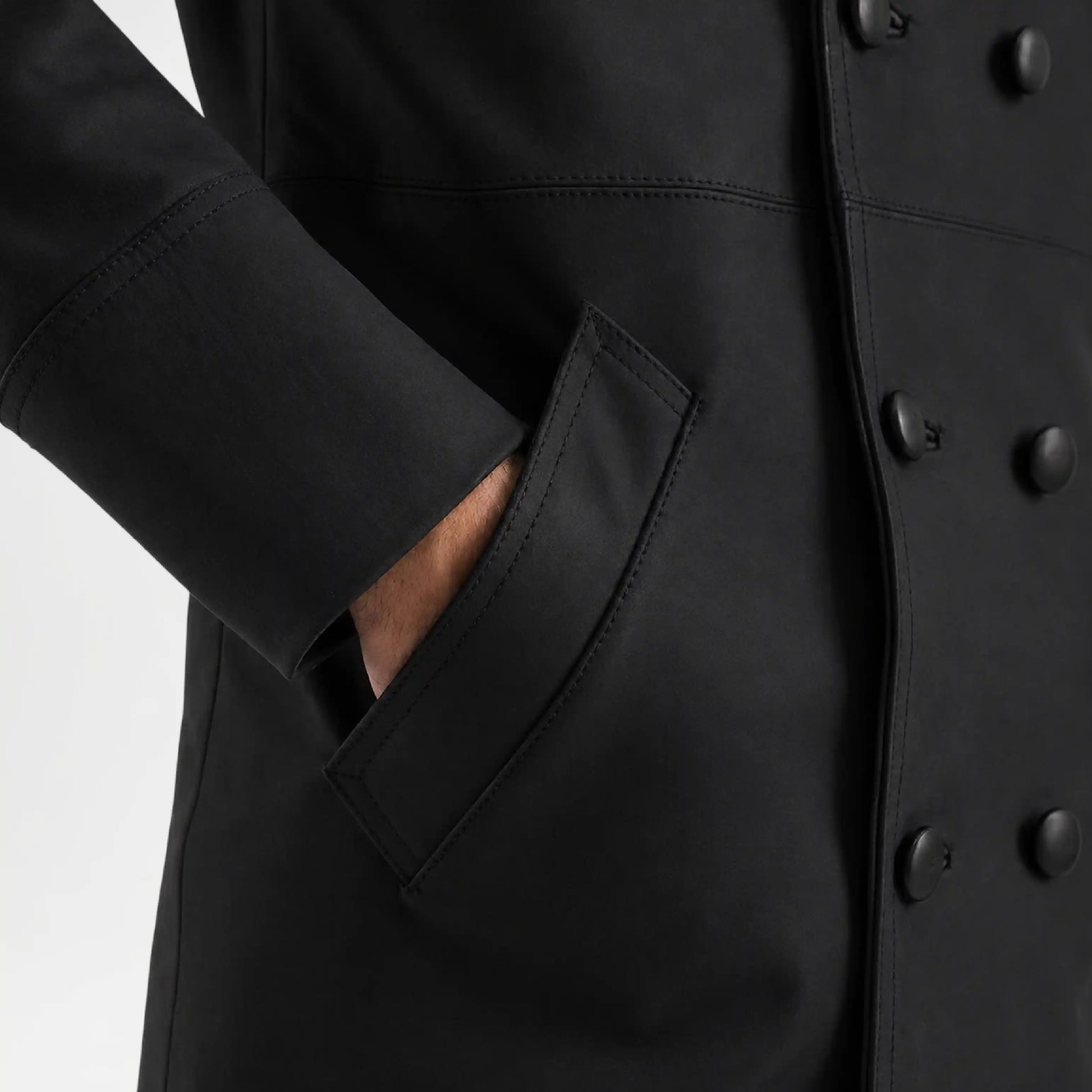 Close-up of a black coat with buttons and a pocket on a white background