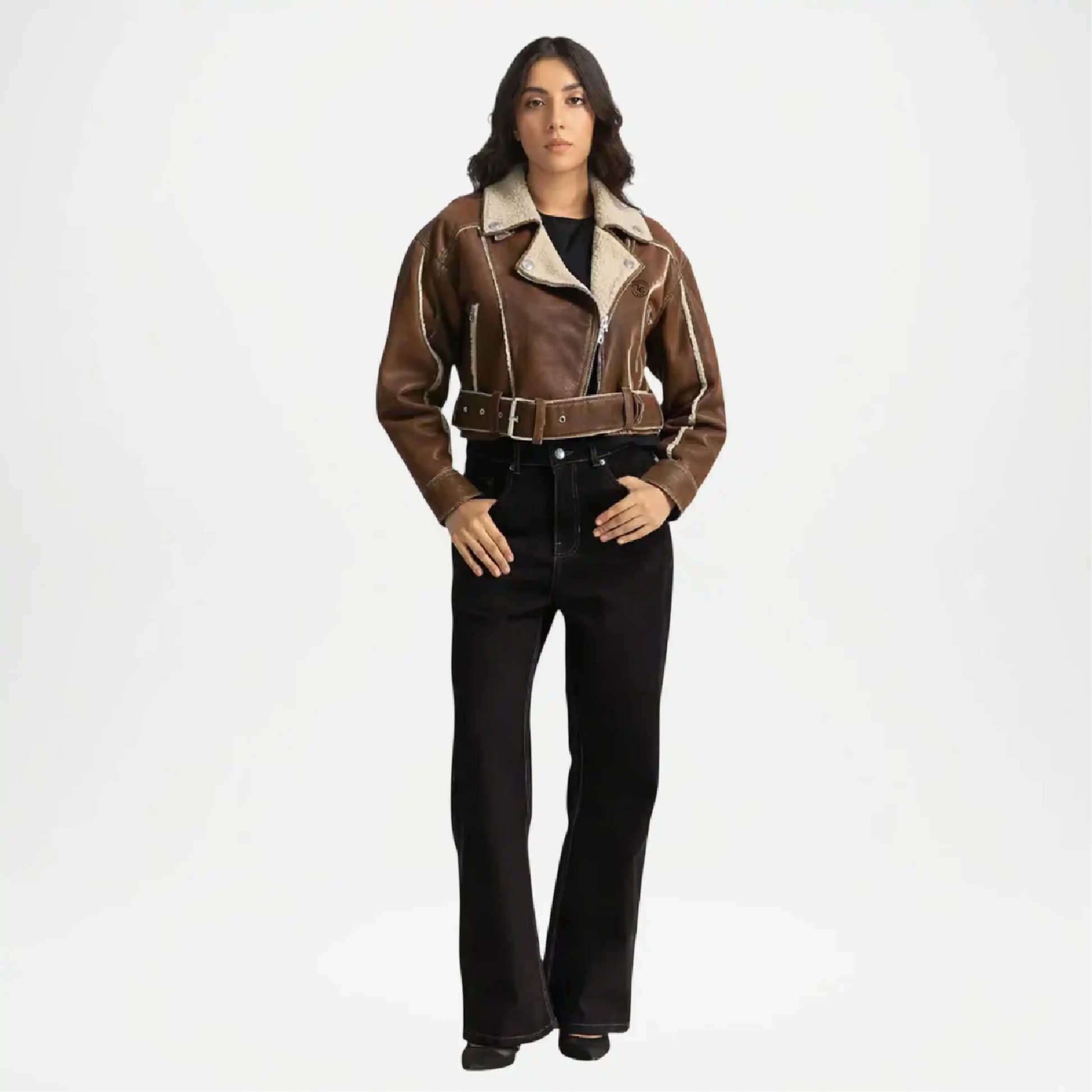 Person wearing a brown shearling jacket and black pants on a white background