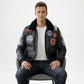 Man wearing a black leather jacket with patches sitting on a chair against a white background
