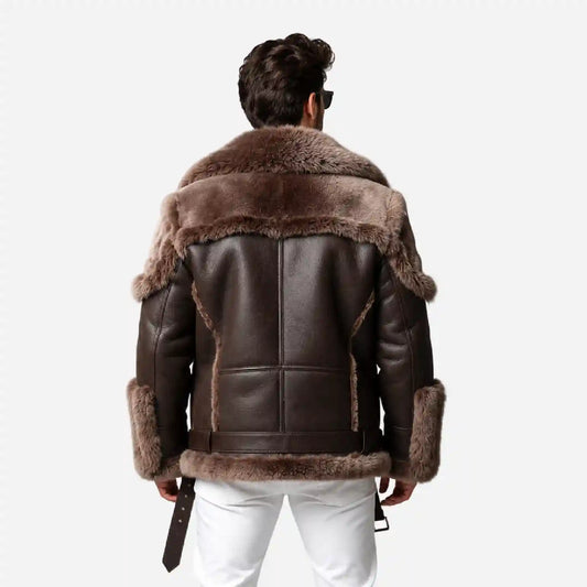 A man viewed from behind wearing a dark brown leather aviator-style jacket with a thick brown fur collar, collar trim, and cuffs, paired with white pants against a light gray background.