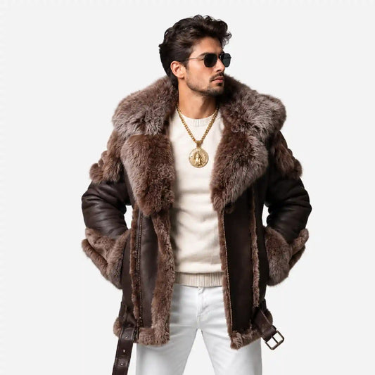 A man wearing a brown and gray fur-trimmed aviator-style jacket over a cream sweater and white pants, photographed against a plain light gray studio background.