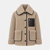A beige sherpa fleece jacket with black contrast piping, a black faux-leather chest pocket with a zipper, and black buttons, shown against a light gray background.