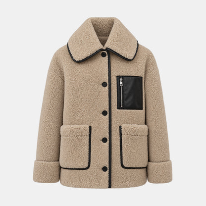 A beige sherpa fleece jacket with black contrast piping, a black faux-leather chest pocket with a zipper, and black buttons, shown against a light gray background.